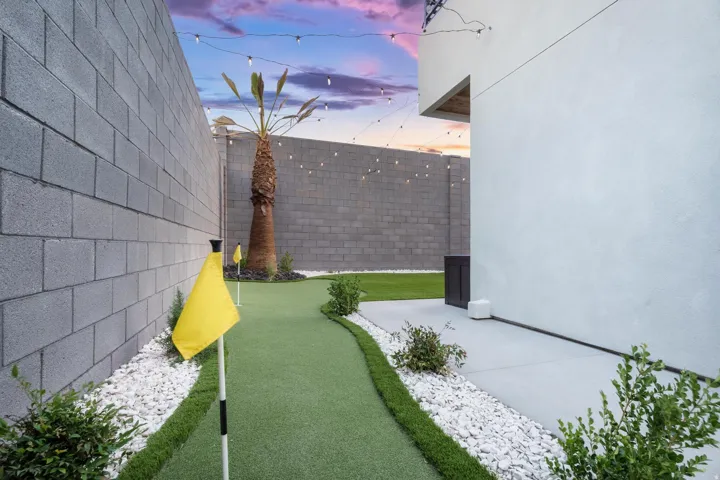 Putting green, paver patio, block walls, string lights, and established palm