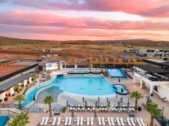 Expansive outdoor aquatic area featuring a large swimming pool, integrated water slide, and wave simulator