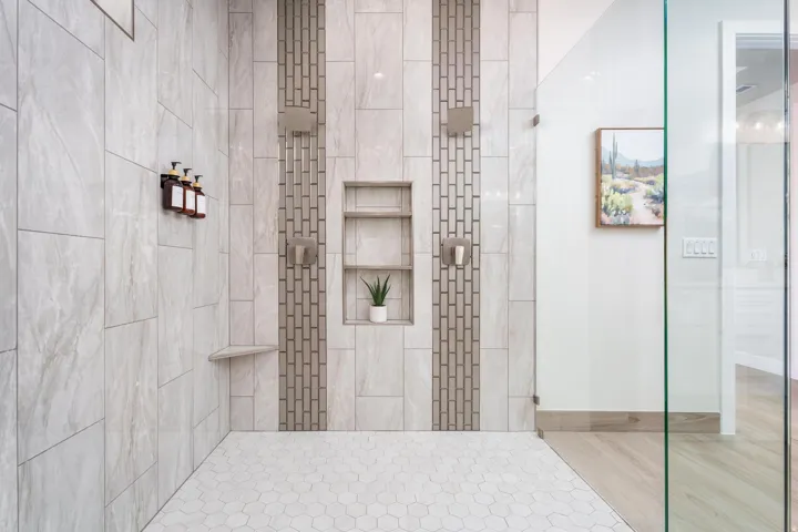 Spacious walk-in shower with dual shower heads, integrated wall niches, built-in corner bench, and glass enclosure