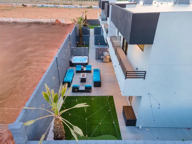 Private backyard space featuring a built-in hot tub, artificial turf putting green, and a second-story balcony