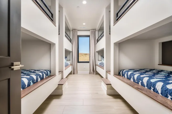 Built-in bunk beds with wood-finish trim, recessed lighting, and a single window with curtain panels