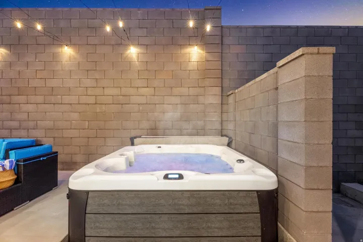 Built-in spa with integrated lighting, surrounded by concrete block walls and illuminated by string lights