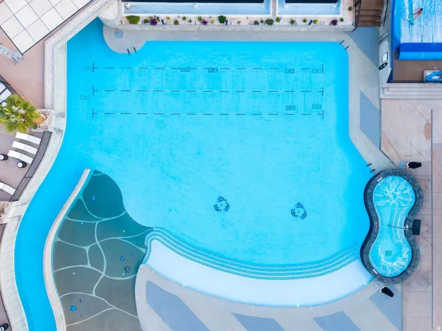 Expansive aquatic amenity featuring a large swimming pool, integrated spa, and a separate shallow water play area