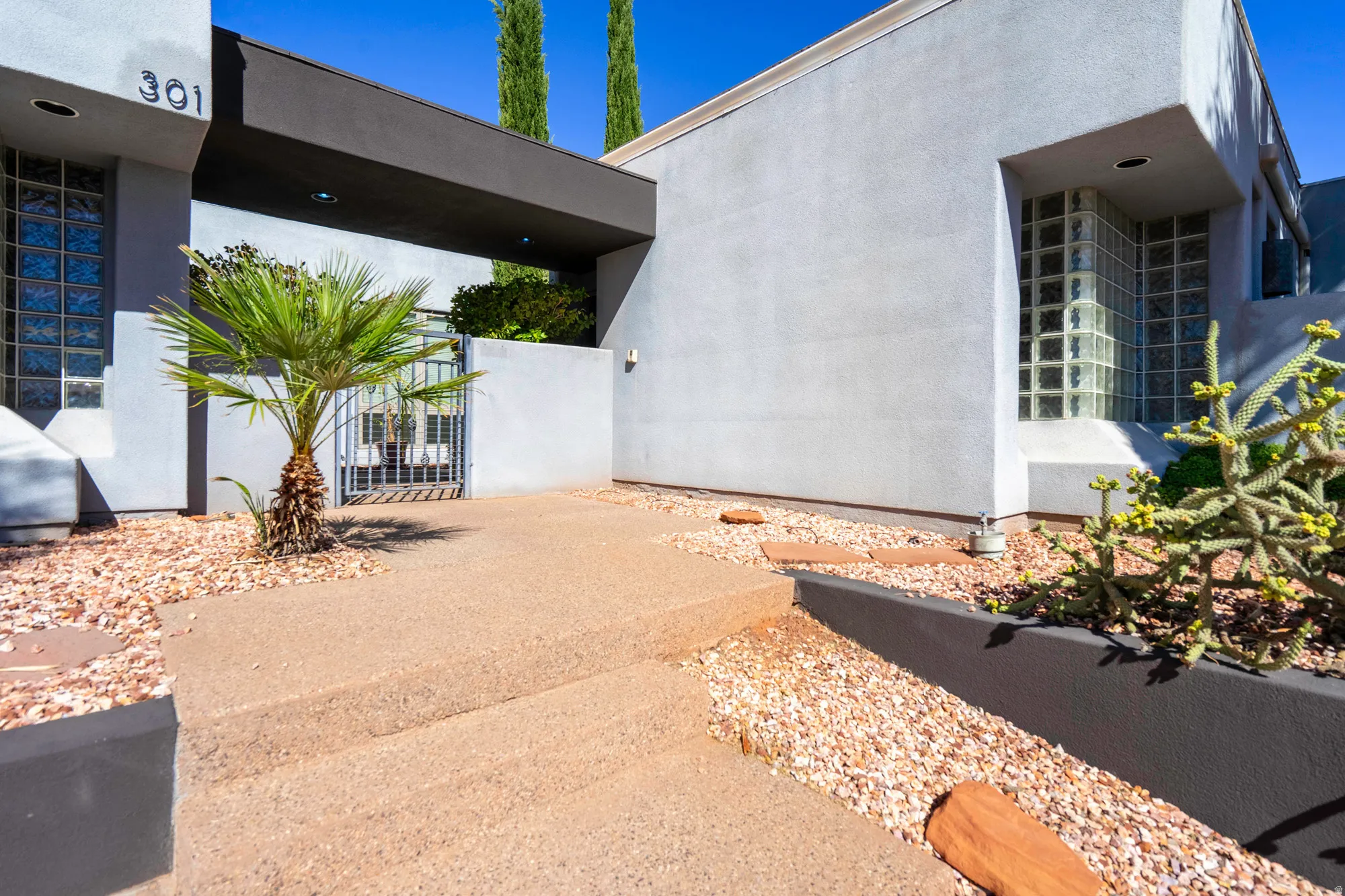 Stucco exterior with glass block windows, a gated entry, and a covered portico