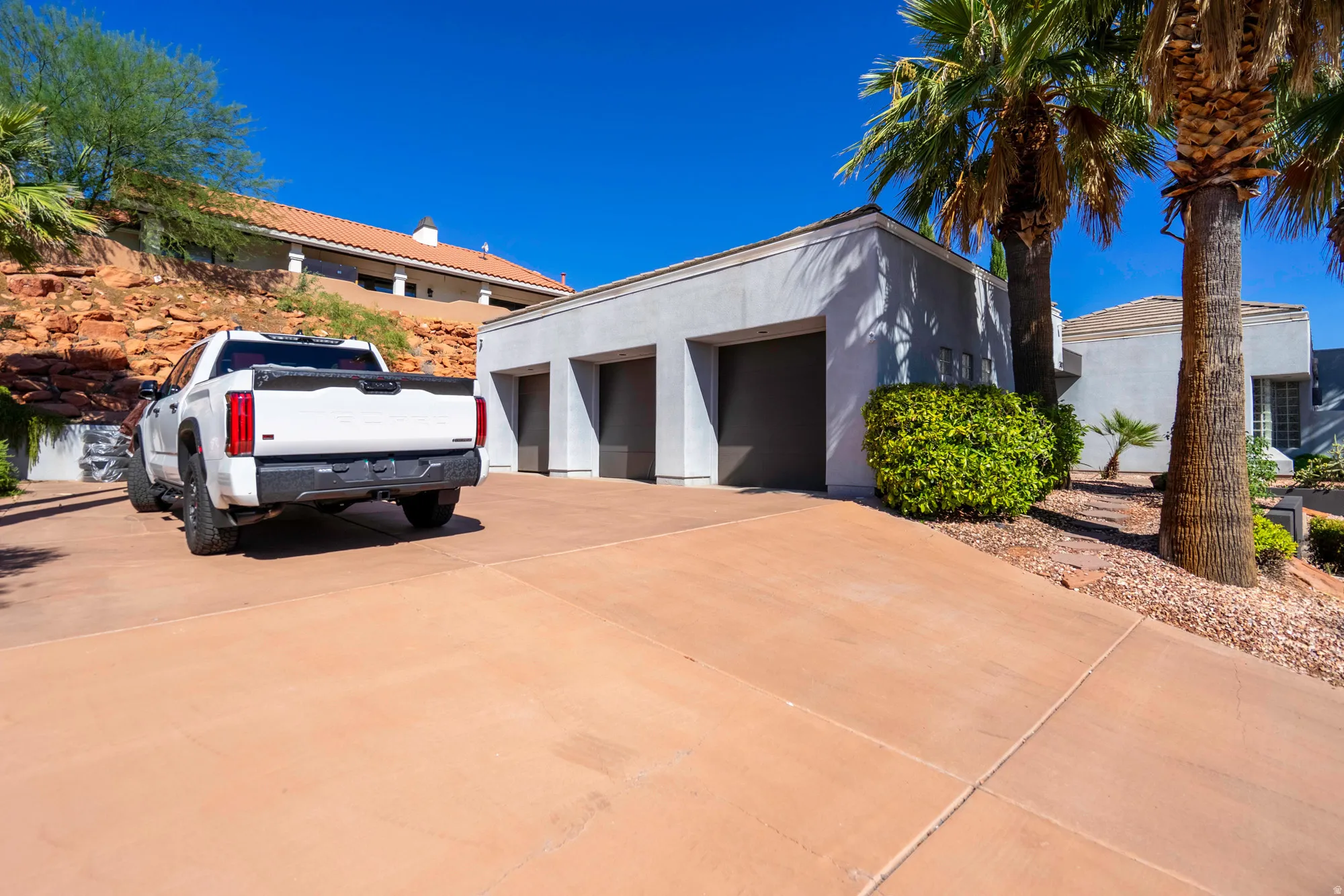 Expansive concrete driveway leading to a three-car garage