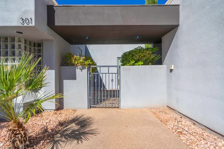Stucco exterior with a covered entry, glass block window, and decorative metal gate