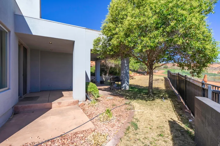Covered patio with recessed lighting, concrete flooring, and direct access to the outdoor area with mature trees and a black metal fence