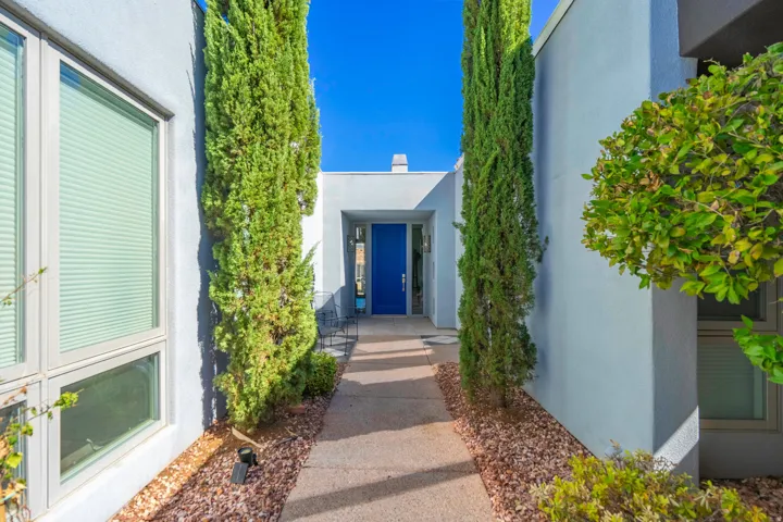 Modern exterior with a vibrant blue entry door, concrete pathway, and landscaped rock beds
