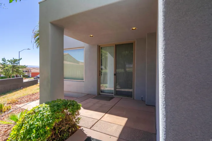 Recessed entryway featuring concrete paver flooring, modern stucco exterior, sliding glass door, and integrated lighting