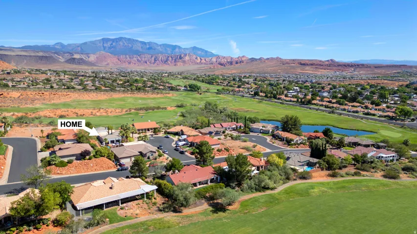 Aerial perspective showcasing the property within a residential development, surrounded by a golf course and natural desert landscaping