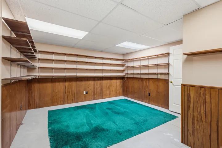 Wood paneling with extensive built-in shelving, dropped ceiling, and recessed lighting