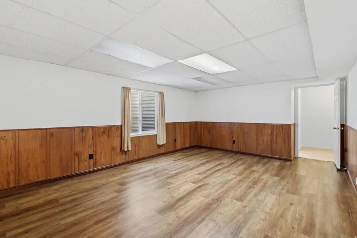 Wood-finish flooring with wood paneling and white walls