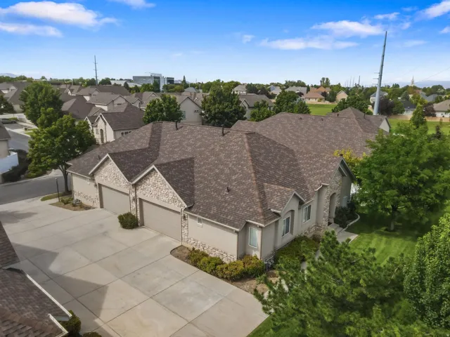 Multi-level roofline, stone and stucco exterior, attached two-car garage, concrete driveway, and established landscaping