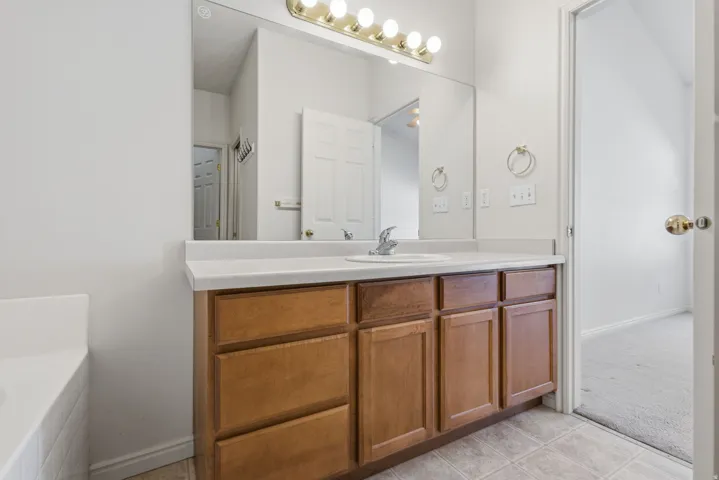 Bathroom vanity with a white countertop, integrated sink, and wood-finish cabinetry