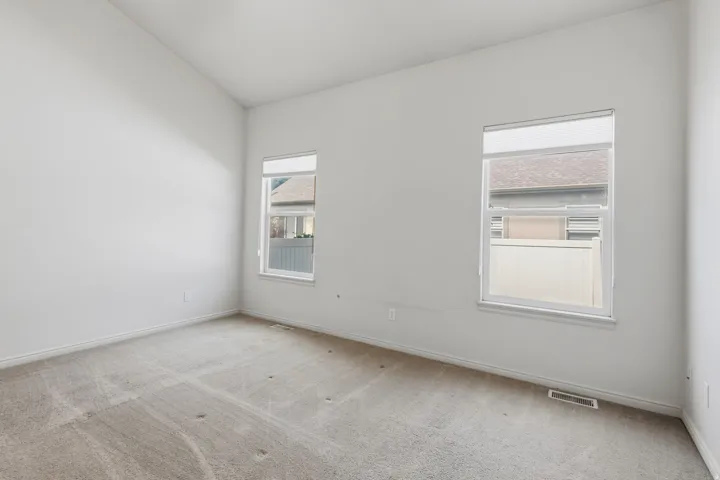 Vaulted ceiling, two windows, and light neutral carpeting