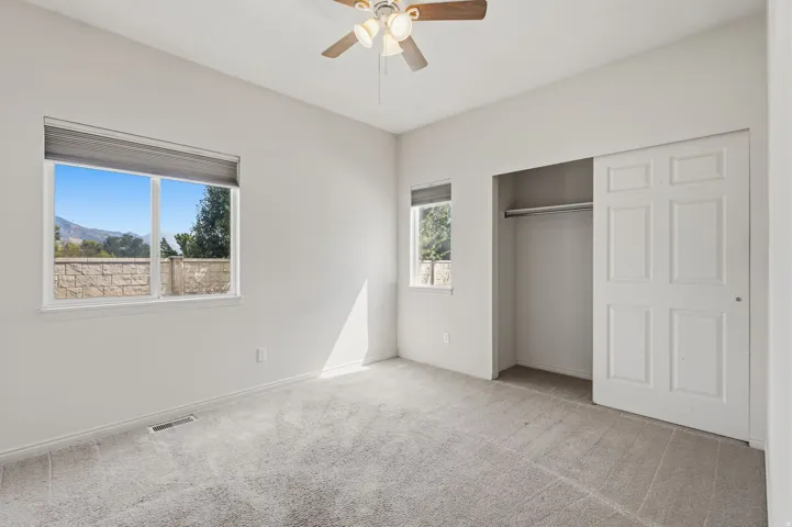 Plush carpeting, dual windows, and ceiling fan with integrated lighting