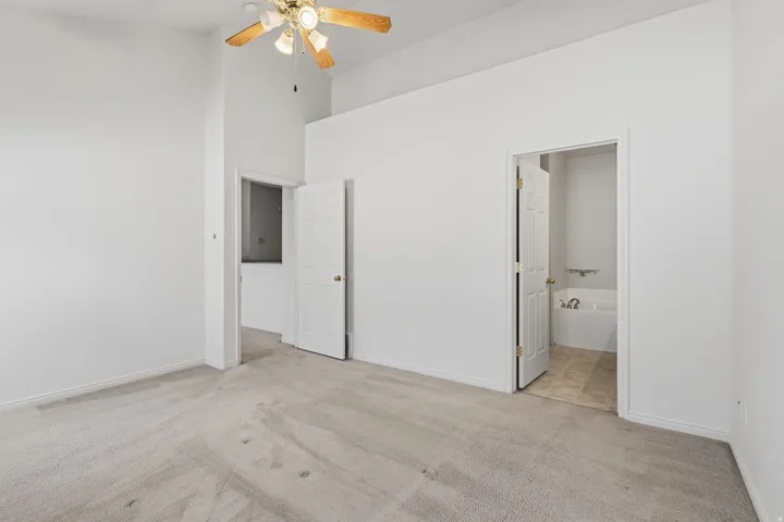 Vaulted ceiling, ceiling fan, plush carpet flooring, white paneled doors, built-in bathtub