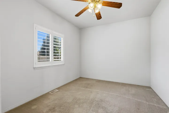 Window with white plantation shutters and a ceiling fan with light fixture