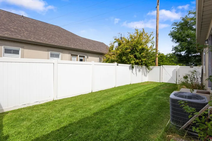 Enclosed backyard featuring a manicured lawn, white privacy fencing, and a white fence gate