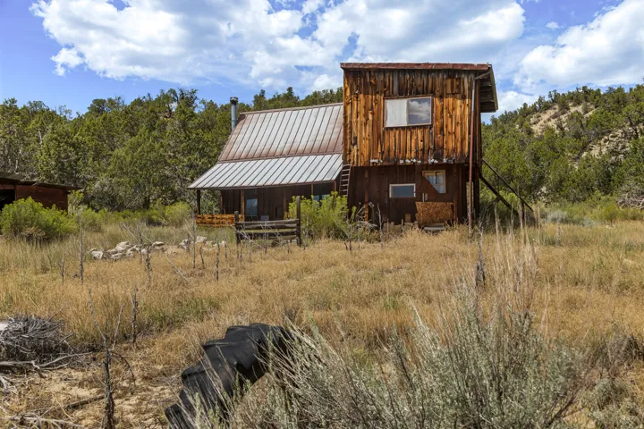 Two-story board-and-batten cabin, standing-seam metal roof, covered porch. Structure is not habitable and unsafe to enter — exterior viewing only. Sold as-is