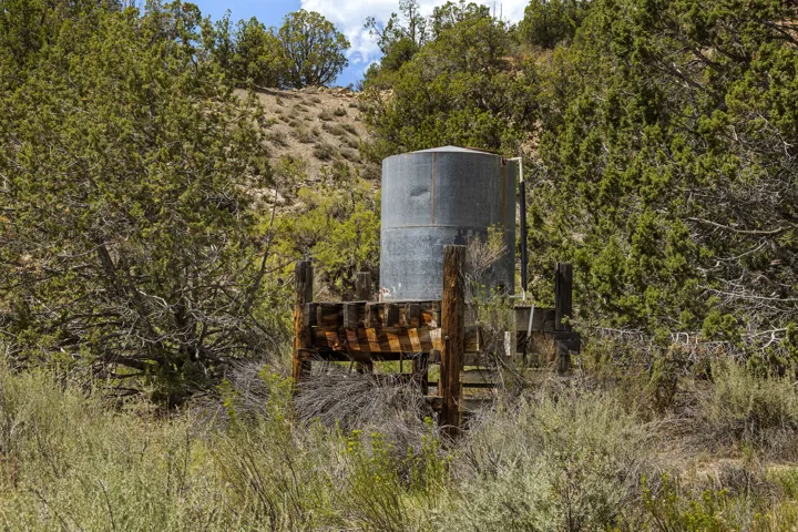 Gravity-fed galvanized storage tank on timber stand, part of the ranch's developed water system. Water Right No. 81-1776 conveys