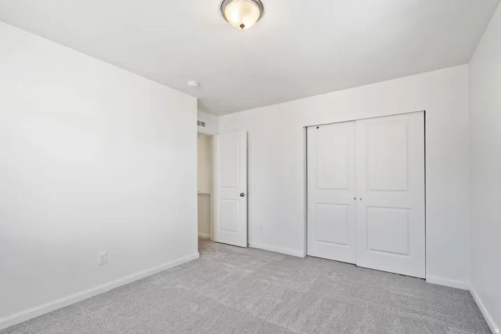 Recessed lighting, light gray carpeting, neutral wall paint, and white trim
