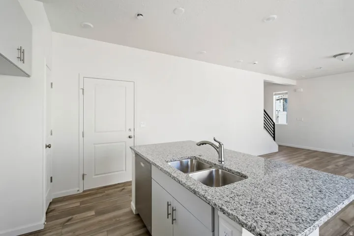 Kitchen island featuring a dual stainless steel sink and speckled stone countertop