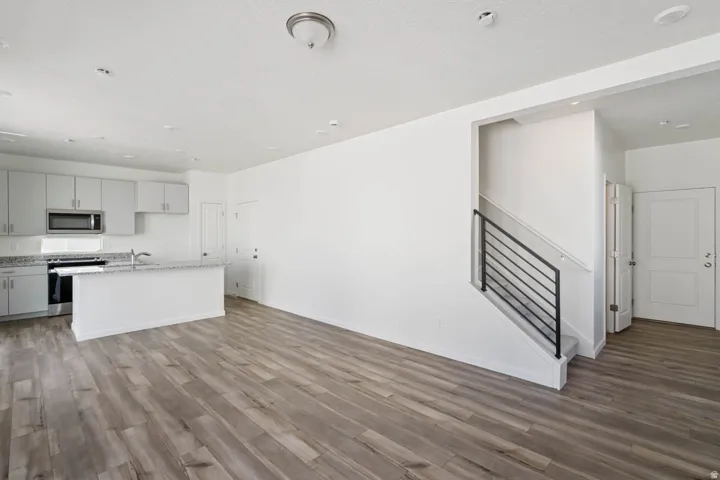 Open-concept living space with wood-finish flooring, a kitchen island, and stainless steel appliances