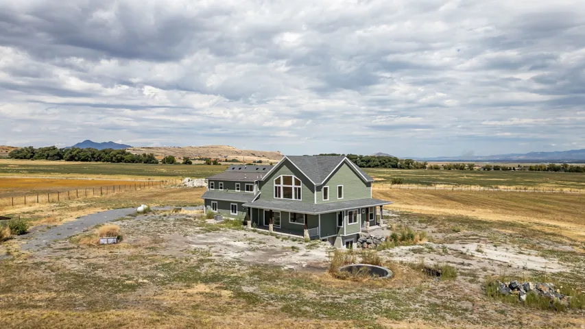 Expansive property featuring a green-sided residence with a covered porch and stone accents