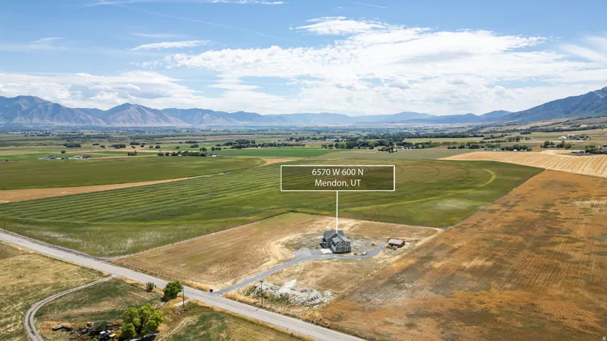 Expansive property set amidst agricultural fields, featuring distant mountain ranges and clear skies