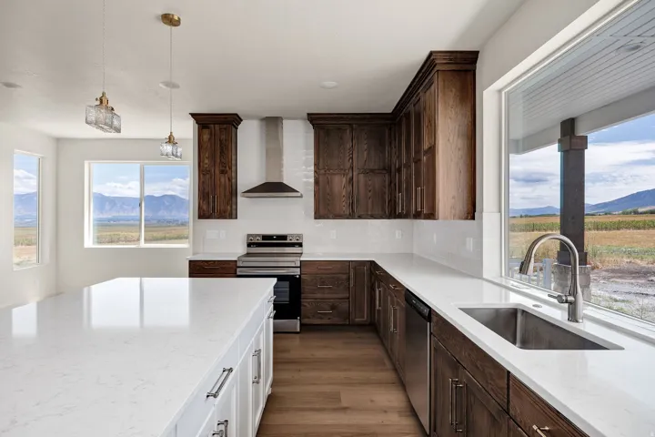 Open-concept kitchen featuring dark wood-finish cabinetry, white countertops, stainless steel appliances, and a central island with pendant lighting