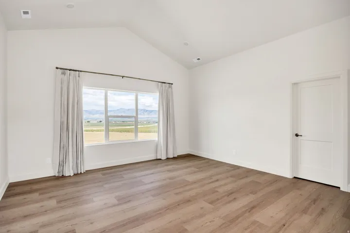 Vaulted ceiling with recessed lighting, expansive window, wood-finish flooring, and a paneled door with matte black hardware