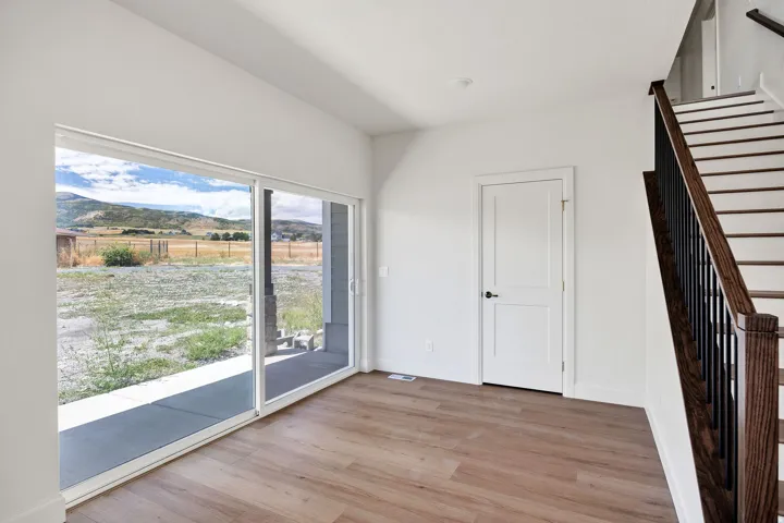 Sliding glass door, wood-finish flooring, white solid core door, dark wood newel post, metal balusters