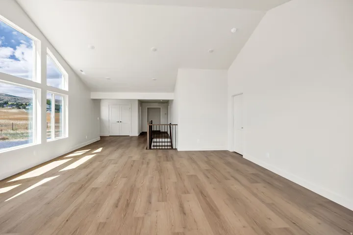 Vaulted ceiling with recessed lighting, large picture windows, wood-finish flooring, white walls, and French entry doors