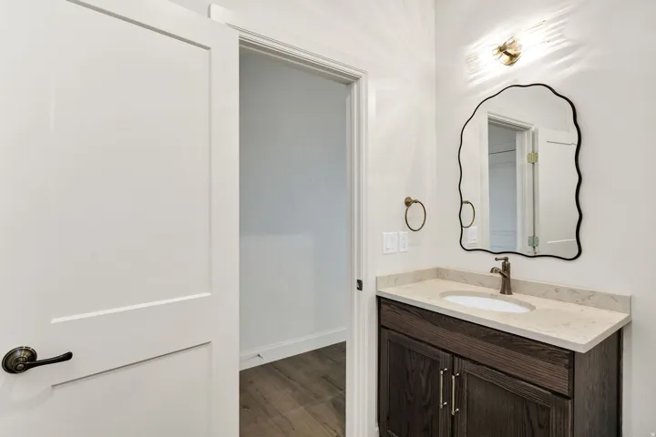 Custom vanity with a light-toned countertop, undermount sink, and bronze-finish faucet
