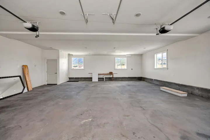 Spacious garage with exposed concrete flooring, multiple windows, and two garage door openers