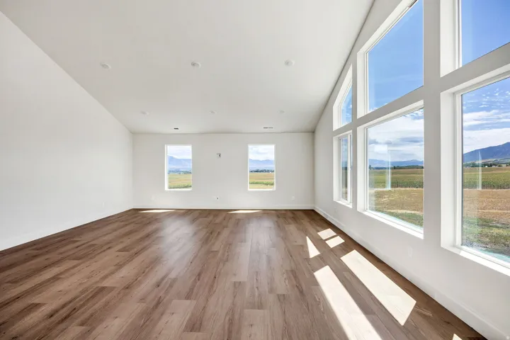 Expansive living area featuring vaulted ceilings, wood-finish flooring, recessed lighting, and large picture windows