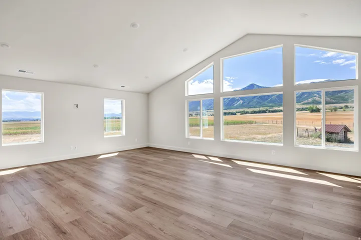 Vaulted ceiling, recessed lighting, wood-finish flooring, expansive windows, mountain backdrop
