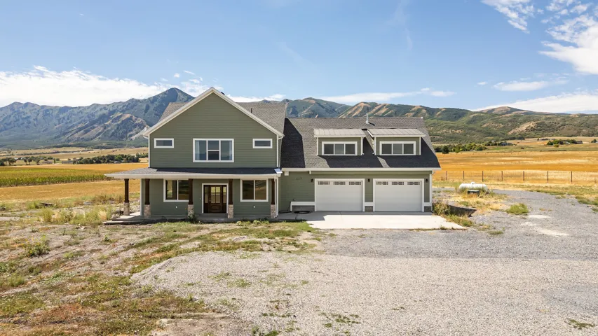 Two-story home with a covered front porch featuring stone accents and wood columns, a two-car garage, and a dormer roofline