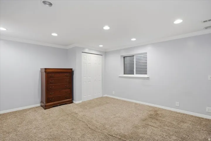 Recessed lighting, light-toned walls, crown molding, white trim, and a white bi-fold closet