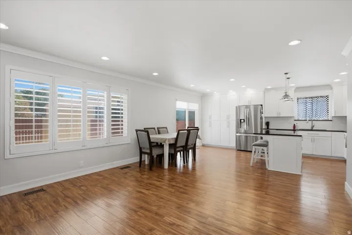 Wood-finish flooring throughout, white plantation shutters, recessed lighting, white cabinetry, and stainless steel appliances