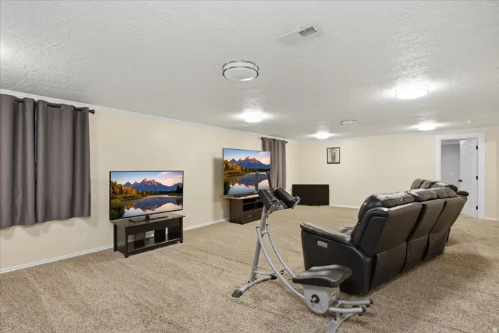 Spacious room with plush carpet flooring, multiple ceiling-mounted light fixtures, and perimeter baseboard trim