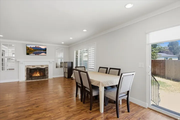 Wood-finish flooring, recessed lighting, and a white fireplace with a stone surround