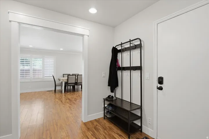 Hardwood-style flooring throughout, recessed lighting, and a wide cased opening into a room featuring plantation shutters