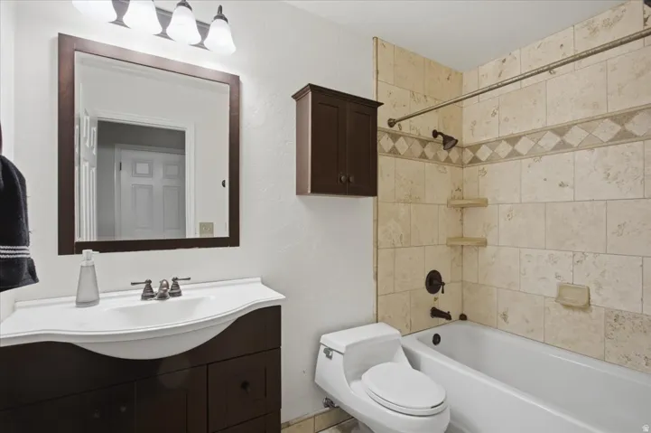 Bathroom featuring a dark wood finish vanity with integrated sink, framed mirror, and three-light fixture