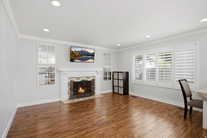 Wood-finish flooring, recessed lighting, crown molding, fireplace with mantel, and plantation shutters