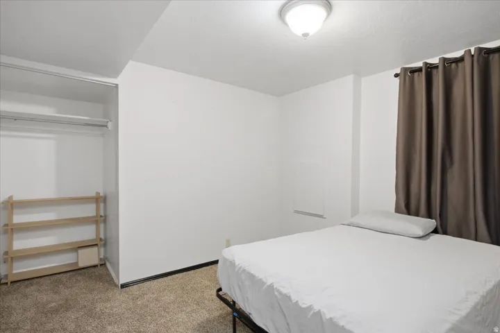 Wall-to-wall carpeting with an open closet featuring a hanging rod