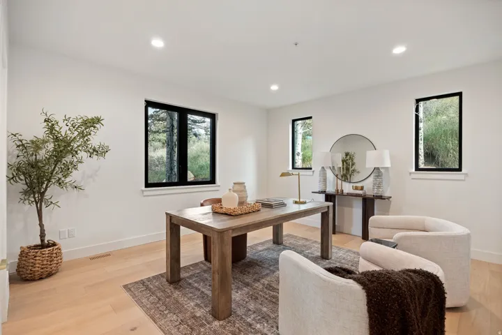 Recessed ceiling lighting, wood-finish flooring, multiple windows with black trim, and white walls