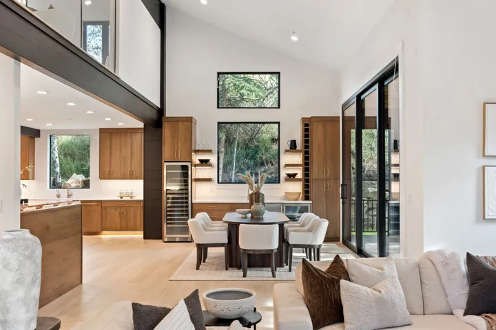 Vaulted ceiling with exposed beams, wood-finish flooring, built-in wine cooler, and expansive sliding glass doors