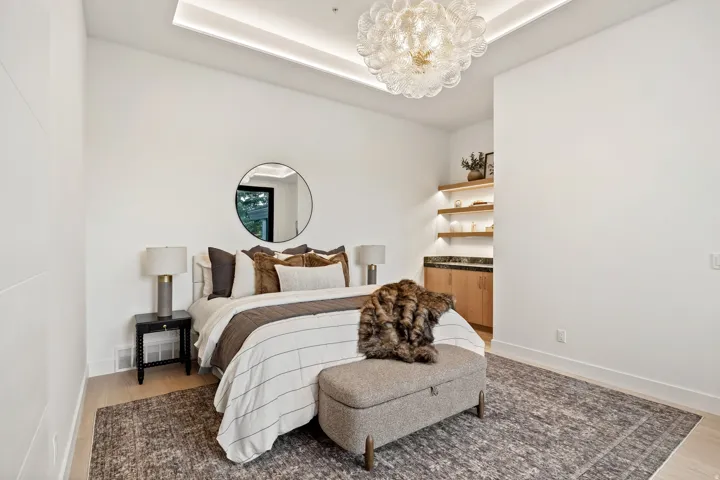 Recessed ceiling lighting, decorative overhead lighting fixture, wood-finish flooring, built-in shelving with integrated lighting, and built-in cabinetry with a stone countertop